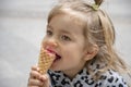 Street portrait of a little girl eating red ice cream in a cone waffle cone. Concept: sweetness for children, summer heat, satisfy Royalty Free Stock Photo