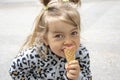 Street portrait of a little girl eating red ice cream in a cone waffle cone. Concept: sweetness for children, summer heat, satisfy Royalty Free Stock Photo