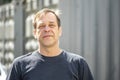 Street portrait of a man 40-50 years old in a black t-shirt on a neutral blurred background. Perhaps he is just a buyer, an actor