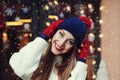 Street portrait of smiling beautiful young woman wearing classic winter knitted clothes. Model looking at camera