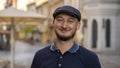 Street portrait of a smiling young man 30 -35 years old in a cap with a beard, looking directly into the camera on a neutral backg Royalty Free Stock Photo