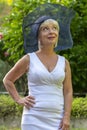 Street portrait of stylish and beautiful blonde woman 60-65 years old in a fashionable hat on the background of nature. Royalty Free Stock Photo