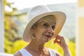 Street portrait of stylish and beautiful blonde woman 60-65 years old in a fashionable hat on the background of nature. Royalty Free Stock Photo