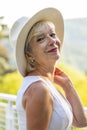 Street portrait of stylish and beautiful blonde woman 60-65 years old in a fashionable hat on the background of nature. Royalty Free Stock Photo