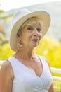 Street portrait of stylish and beautiful blonde woman 60-65 years old in a fashionable hat on the background of nature. Royalty Free Stock Photo