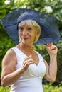 Street portrait of stylish and beautiful blonde woman 60-65 years old in a fashionable hat on the background of nature. Royalty Free Stock Photo