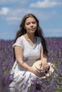 Street portrait of a young girl 17-20 years old in a white dress with long flowing black hair against the sky and lavender field,