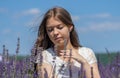 Street portrait of a young girl 17-20 years old in a white dress with long flowing black hair against the sky and lavender field,