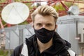 Street portrait of a young man in a black medical mask against the background of telecommunications buildings and satellite dishes Royalty Free Stock Photo