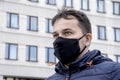 Street portrait of a young man in a jacket and a medical mask on the background of an urban landscape.Concept: health care, life Royalty Free Stock Photo