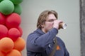 Street portrait of a young man 25-30 years old with blond hair drinking coffee from a paper cup against a background of colorful b Royalty Free Stock Photo