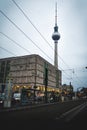 Street with road in Berlin with shopping center and tw tower at Alexanderplatz with dramatic sky. Travel and tourism in Berlin