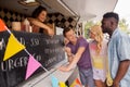 Seller showing menu to customers at food truck