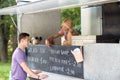 Saleswoman at food truck serving male customer