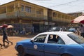 Street scene in the city of Bissau with a taxi and people crossing a dirt road, in Guinea Bissau Royalty Free Stock Photo