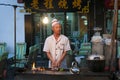 Street scene in the city of Dunhuang, with a cook preparing lamb kebab at a food stall, in China