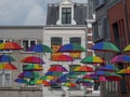 Street scene of multiple colorful umbrellas suspended from buildings. Nijmegen, Netherlands.