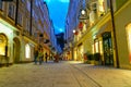 Street scene, people walking along narrow road between tall trad