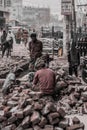 Street scene of workers breaking bricks by hand to reuse them on the streets, Dhaka, Bangladesh