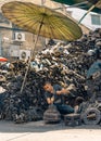 Street scrap yard worker with mountain of engine pieces surrounding him.