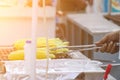 Street seller flipping corn on grill