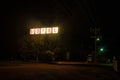 Neon sign of a cheap motel, a large truck looming in the background.