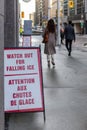 Street sign on the sidewalk warning of the danger of ice and snow falling from the building Royalty Free Stock Photo