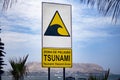 Street sign of `tsunami hazard zone` meeting point beside the ocean