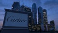 Street signage board with Cartier logo in the evening. Blurred business district skyscrapers background. Editorial 3