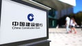 Street signage board with China Construction Bank logo. Blurred office center and walking people background. Editorial