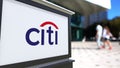 Street signage board with Citigroup logo. Blurred office center and walking people background. Editorial 3D rendering