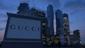Street signage board with Gucci logo in the evening. Blurred business district skyscrapers background. Editorial 3