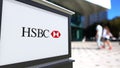 Street signage board with HSBC logo. Blurred office center and walking people background. Editorial 3D rendering