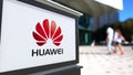 Street signage board with Huawei logo. Blurred office center and walking people background. Editorial 3D rendering