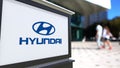 Street signage board with Hyundai Motor Company logo. Blurred office center and walking people background. Editorial 3D