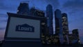 Street signage board with Lowe`s logo in the evening. Blurred business district skyscrapers background. Editorial 3D