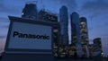 Street signage board with Panasonic Corporation logo in the evening. Blurred business district skyscrapers backgroun