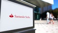 Street signage board with Santander Serfin logo. Blurred office center and walking people background. Editorial 3D