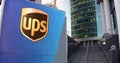 Street signage board with United Parcel Service UPS logo. Modern office center skyscraper and stairs background