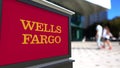 Street signage board with Wells Fargo logo. Blurred office center and walking people background. Editorial 3D rendering