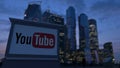 Street signage board with YouTube logo in the evening. Blurred business district skyscrapers background. Editorial 3