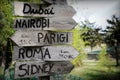 Street signs in the natural park indicating directions to different places of the world. Green plants on the background. Royalty Free Stock Photo