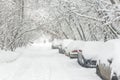 Street during snowfall at winter, Moscow, Russia. Parked cars covered with snow. Scenic view of a snowy city street