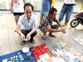 The street stall, selling old books and ancient coins. People are watching, and buying