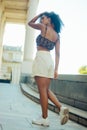 Street-style of a casual Afro-Columbian woman with curly hair wearing stylish crop top and shorts