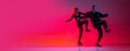 Dynamic young man and woman dancing hip-hop isolated on gradient pink studio background in neon light. Flyer Royalty Free Stock Photo