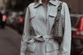 Street style outfit, fashionable woman wearing creme white coat, bag with print and boots on