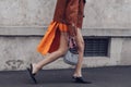 Street style, woman wearing a black turtleneck top, orange mini skirt with train, black heels and Prada bag
