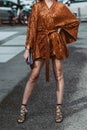 Street style, woman wearing orange belted short dress and black shiny leather laces heels shoes