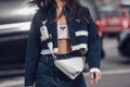 Street style, woman wearing Prada outfit: pale pink cropped top from Prada, white leather cross body bag, navy blue denim jacket Royalty Free Stock Photo